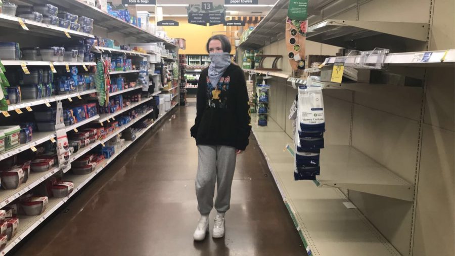 Teenager walks the empty aisles of a grocery store while practicing social distancing