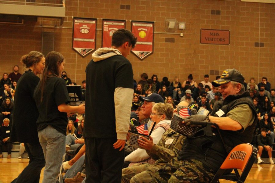 stuco hands out gift baskets during Veterans Day assembly