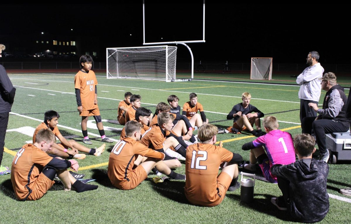 The boys’ soccer team sits in a team huddle.