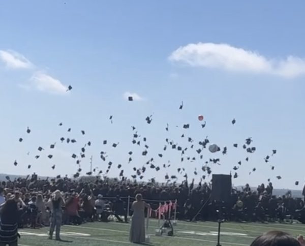 The senior class of 2023 throw their caps in the air.
