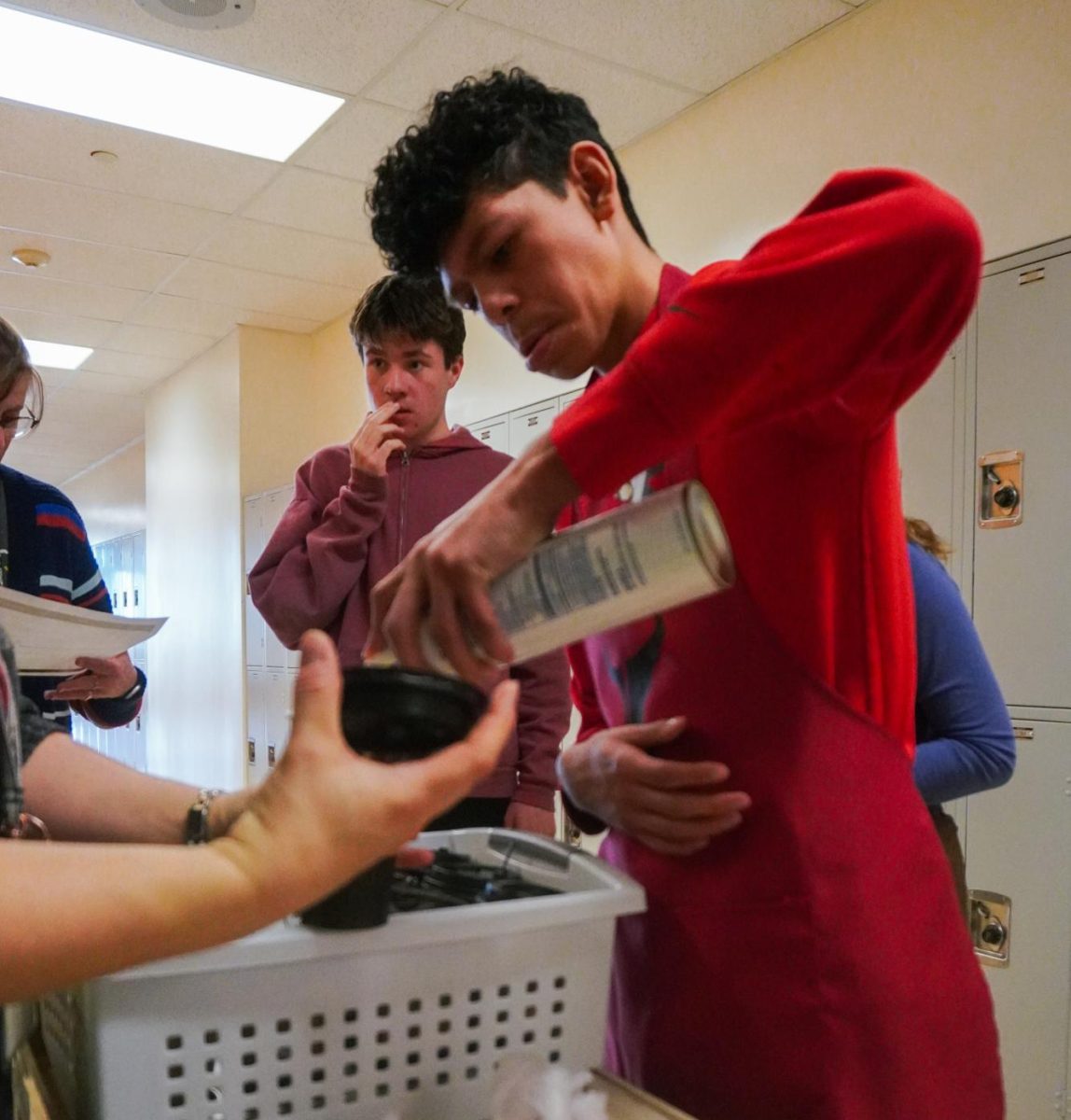 Jayden Berumen ('29) adds whipped cream to a drink prior to handing it out. 